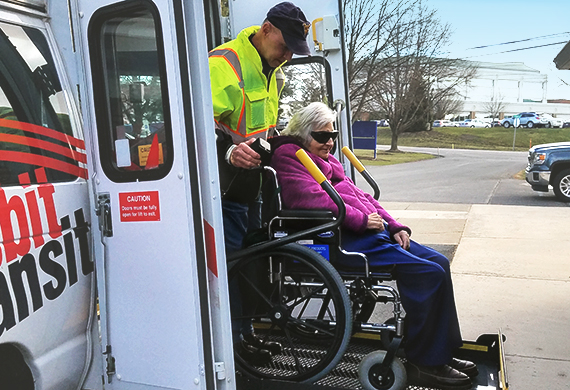 accessibility image featuring a woman in wheelchair being assisted on a lift