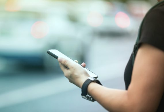 Woman hands using smartphone at city street side,checking the ride-hailing apps