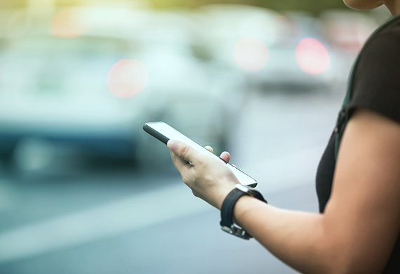 Woman hands using smartphone at city street side,checking the ride-hailing apps