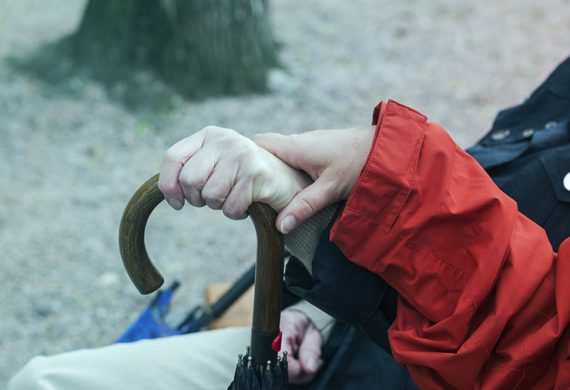 Hands of two women holding the handle of an umbrella